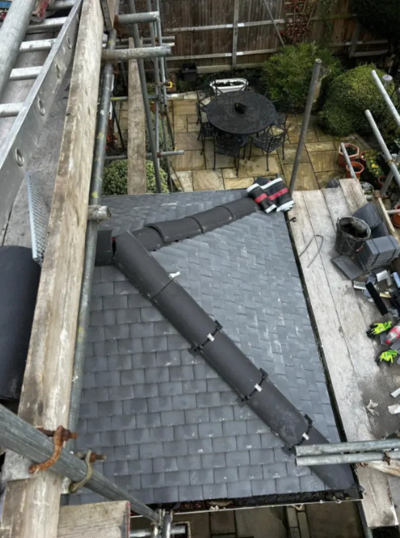 Small pitched roof over a rear bay re-tiled in slate-effect tiles with new dry ridge and hip fittings, seen from the scaffold