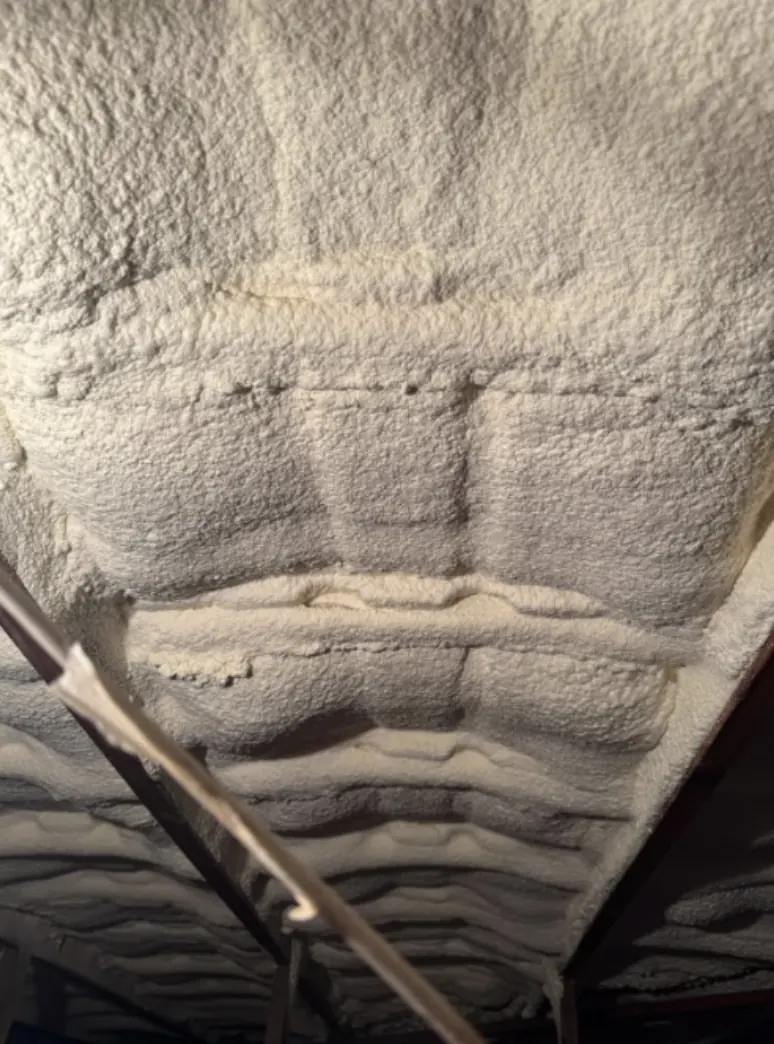Dense white spray foam covering the whole underside of a roof, rafters buried